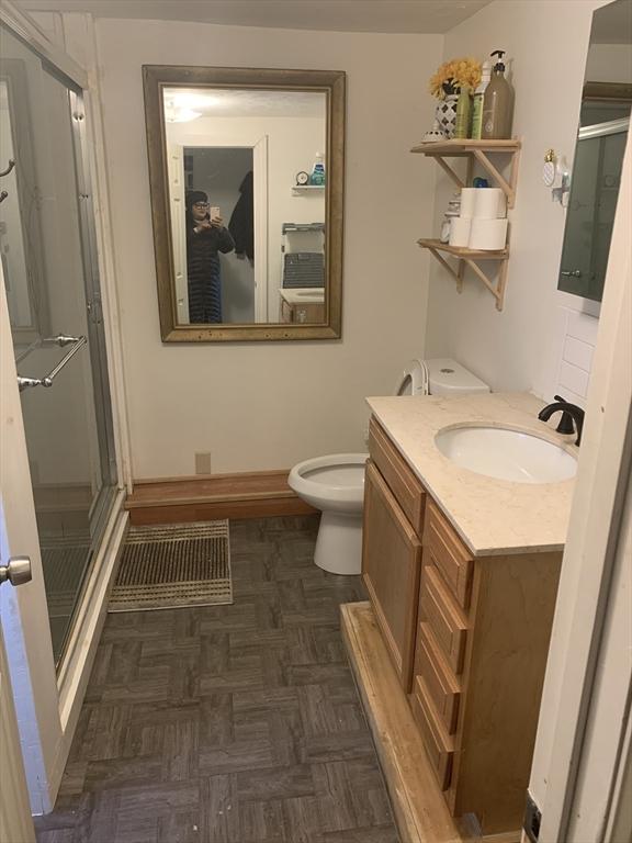 bathroom featuring toilet, a shower with shower door, and vanity