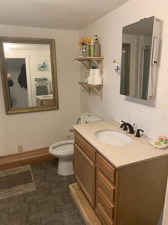 bathroom featuring toilet, decorative backsplash, parquet floors, and vanity