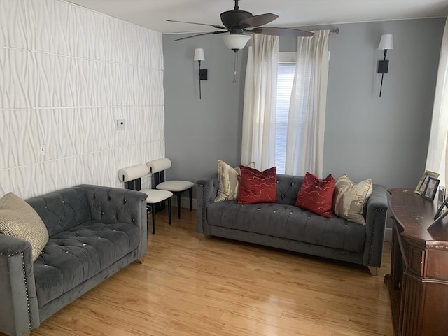 living room featuring light wood-type flooring, ceiling fan, and tile walls