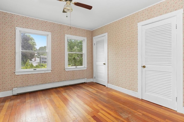 14 Farrell St, Newburyport, MA 01950 - unfurnished bedroom featuring a baseboard radiator, light wood finished floors, crown molding, multiple closets, and wallpapered walls