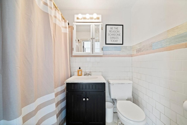 bathroom featuring vanity, toilet, tile walls, and a wainscoted wall