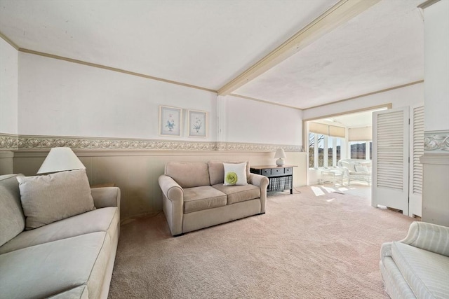 carpeted living room featuring crown molding and a wainscoted wall