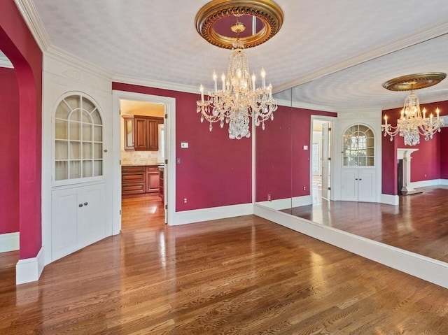 unfurnished dining area with hardwood / wood-style flooring, crown molding, and a notable chandelier