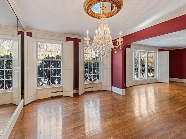 unfurnished dining area featuring ornamental molding, wood-type flooring, a chandelier, and baseboard heating