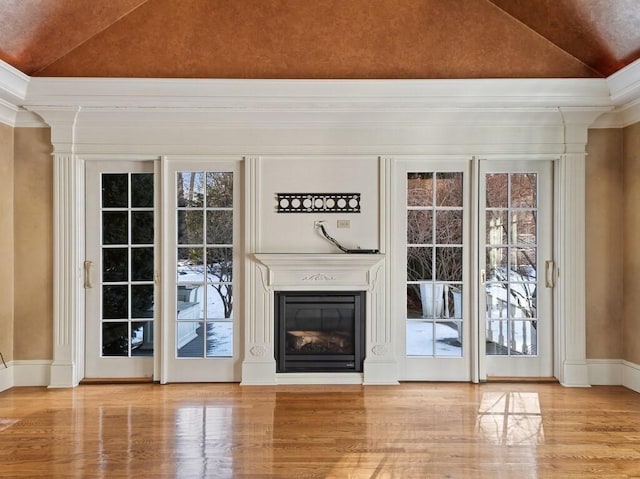 unfurnished living room featuring vaulted ceiling, ornamental molding, and light wood-type flooring