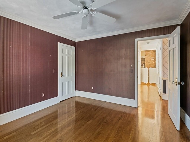 empty room with hardwood / wood-style flooring, ceiling fan, and crown molding