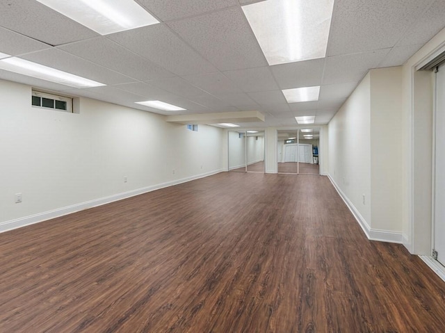 basement featuring a paneled ceiling and dark hardwood / wood-style flooring