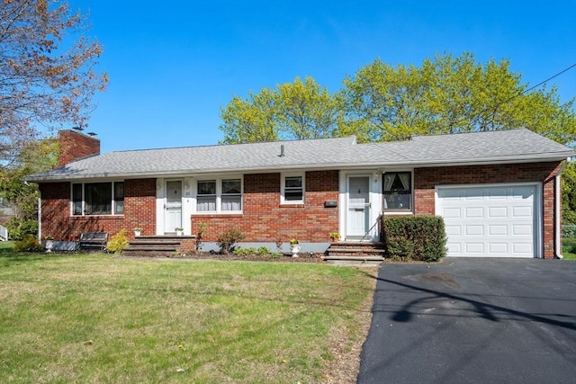 ranch-style home featuring an attached garage, a front lawn, aphalt driveway, brick siding, and a chimney