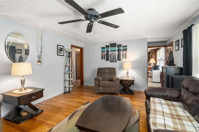 living room featuring baseboards, ceiling fan, and wood finished floors