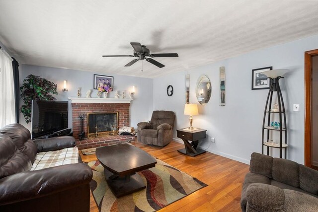 living area with ceiling fan, light wood-type flooring, baseboards, and a fireplace