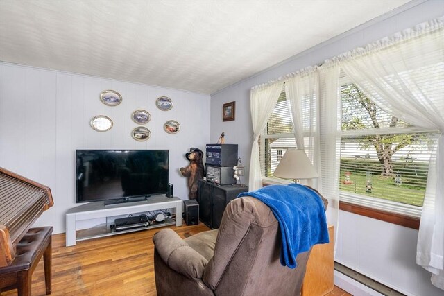 living area with a baseboard radiator, ornamental molding, and wood finished floors