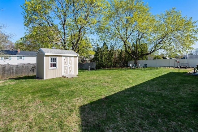 view of yard with a storage unit, a fenced backyard, and an outbuilding