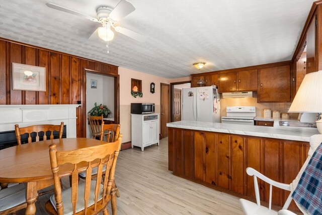 kitchen featuring ceiling fan, white appliances, light countertops, a peninsula, and under cabinet range hood