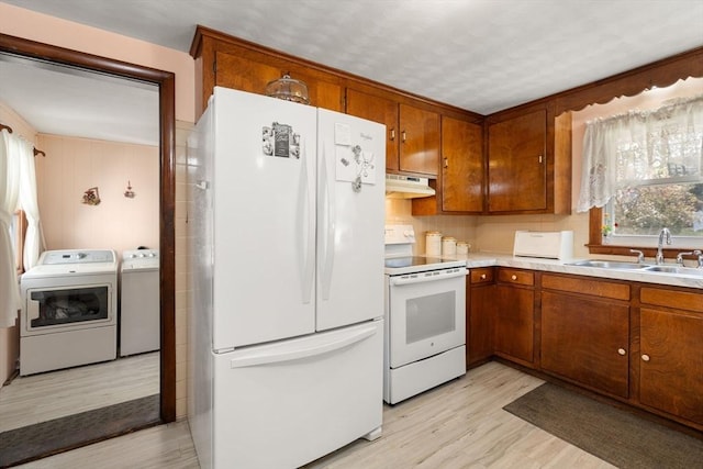 kitchen with a sink, washer and clothes dryer, brown cabinets, and white appliances