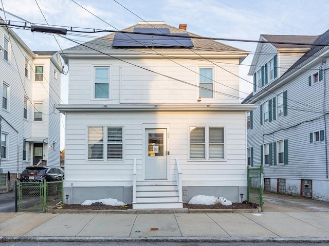 traditional style home with entry steps, fence, and solar panels