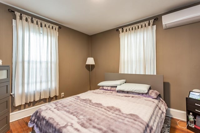 bedroom with dark wood finished floors and an AC wall unit