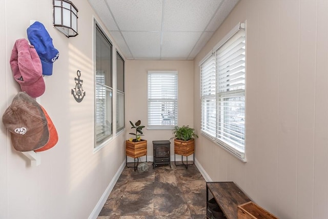 hallway featuring a paneled ceiling and baseboards