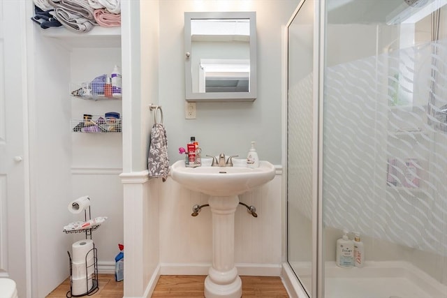 full bathroom with wood finished floors, a shower stall, and baseboards