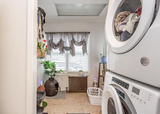 laundry room with stacked washer and dryer, radiator heating unit, and laundry area