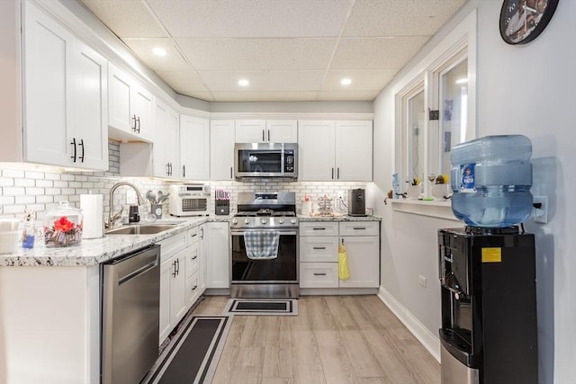 kitchen featuring stainless steel appliances, white cabinetry, a sink, and light wood finished floors