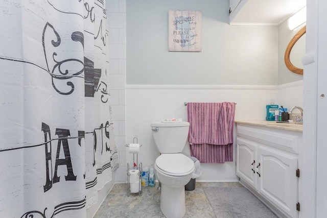 bathroom with toilet, a wainscoted wall, tile walls, and vanity