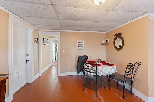dining room with crown molding, wood finished floors, baseboards, and a drop ceiling