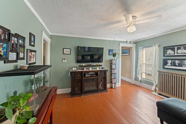 living room with ceiling fan, a textured ceiling, crown molding, and wood finished floors