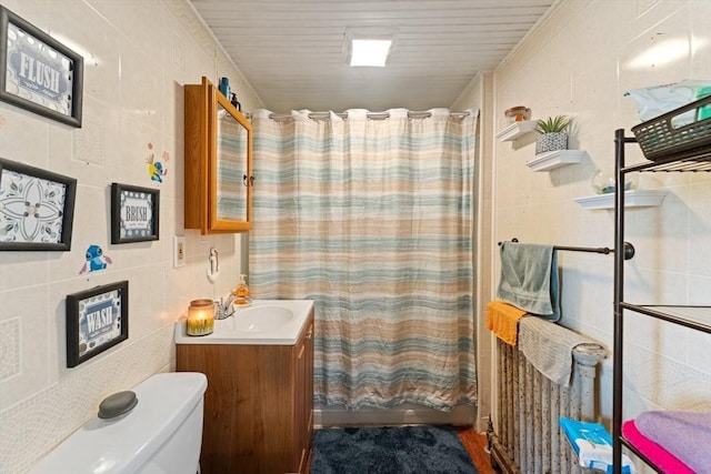 full bath with toilet, tile walls, vanity, and shower / bath combo