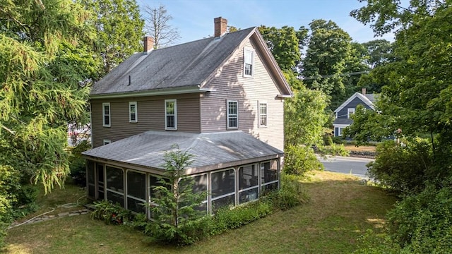 rear view of house with a sunroom and a lawn