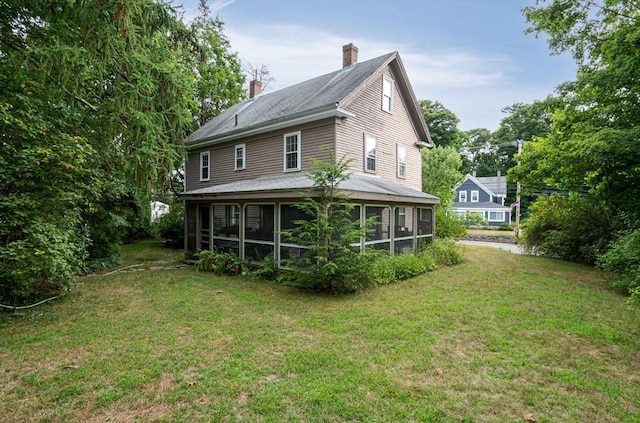 rear view of property with a yard and a sunroom