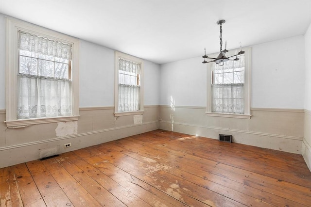 unfurnished dining area with a notable chandelier and wood-type flooring