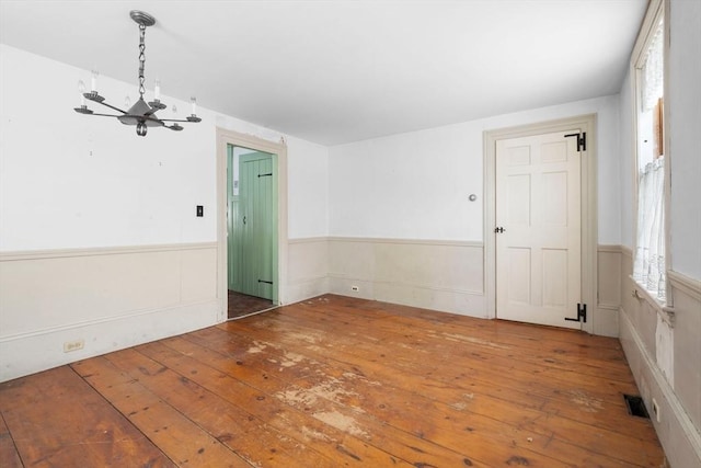 empty room featuring a notable chandelier and wood-type flooring