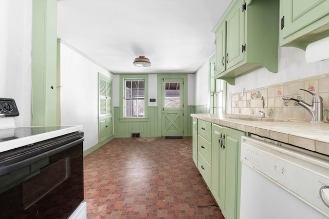 kitchen with crown molding, green cabinetry, range with electric stovetop, tile counters, and dishwasher