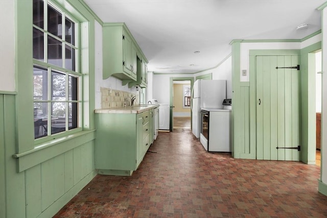 kitchen with washer / dryer, sink, crown molding, range, and decorative backsplash