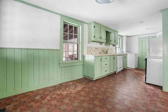 kitchen with washer / dryer, sink, wood walls, green cabinetry, and dishwasher