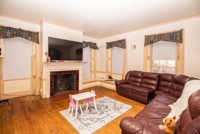 living room with a tile fireplace, hardwood / wood-style floors, and ornamental molding