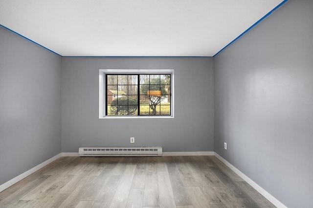 empty room featuring baseboard heating and light wood-type flooring