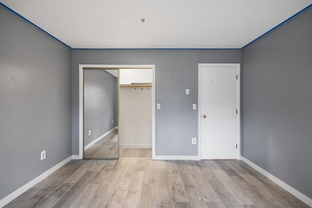 unfurnished bedroom with light wood-type flooring and a closet