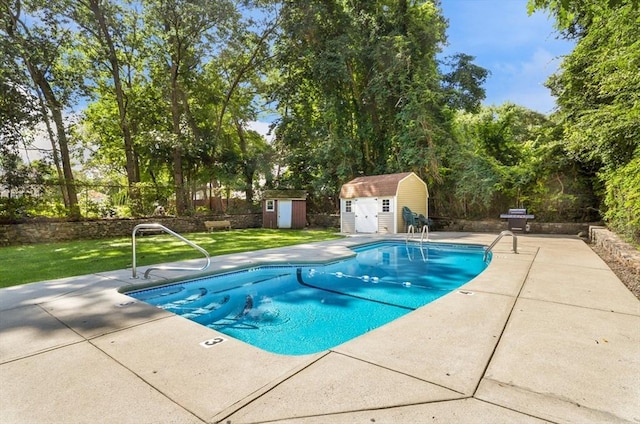 view of swimming pool featuring a lawn, a patio, and a shed