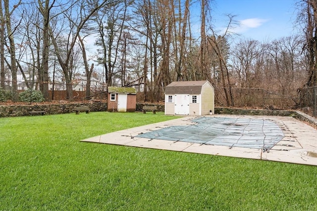 view of yard with a patio, a covered pool, and a storage unit