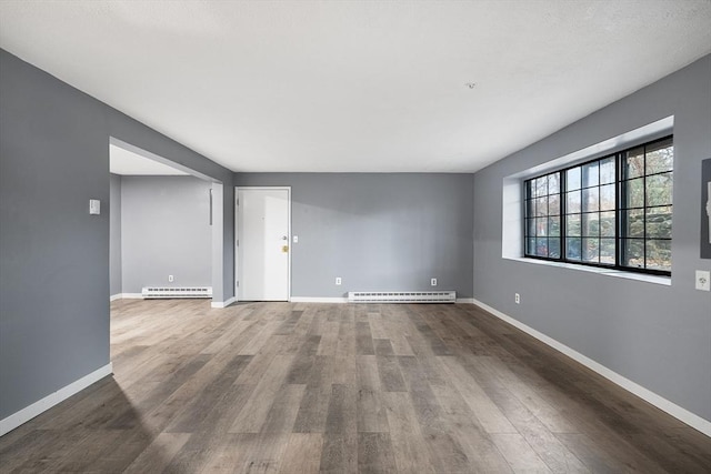 empty room featuring baseboard heating and hardwood / wood-style floors