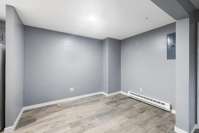 unfurnished room with light wood-type flooring, baseboard heating, and electric panel