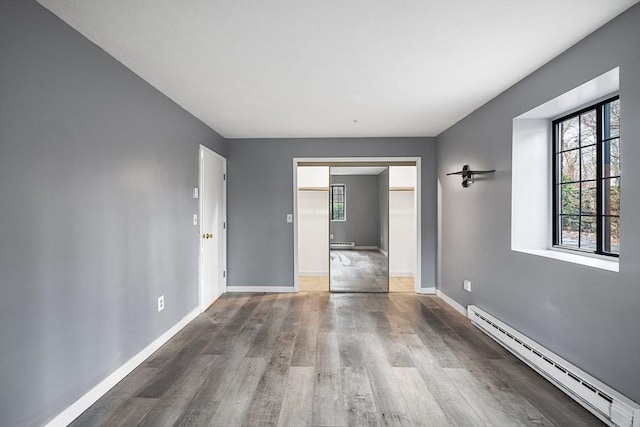 unfurnished room featuring baseboard heating and hardwood / wood-style flooring