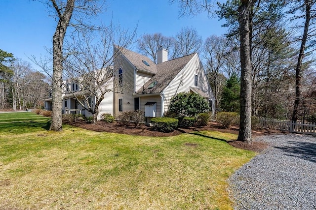 view of home's exterior with a lawn, roof with shingles, a chimney, and fence