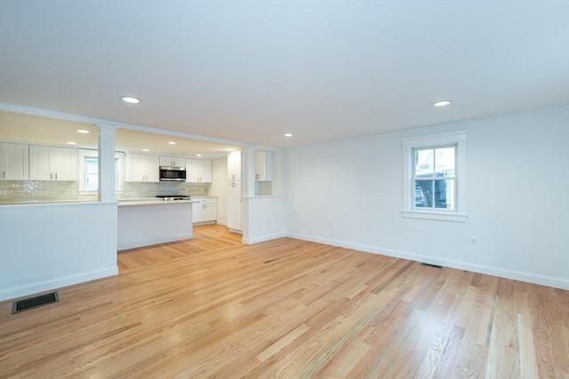 unfurnished living room with baseboards, visible vents, and light wood-style floors