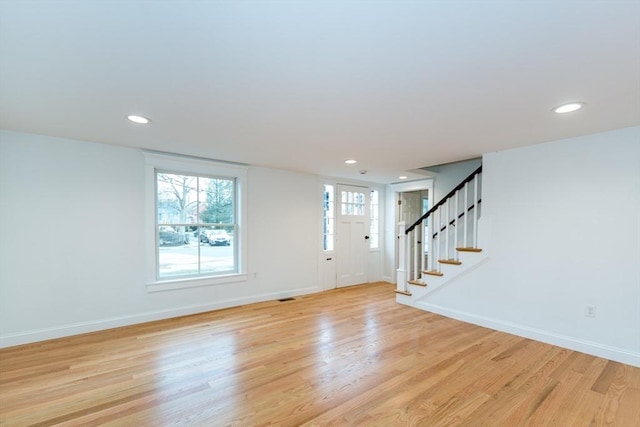 entryway with light wood-style floors, stairs, and baseboards