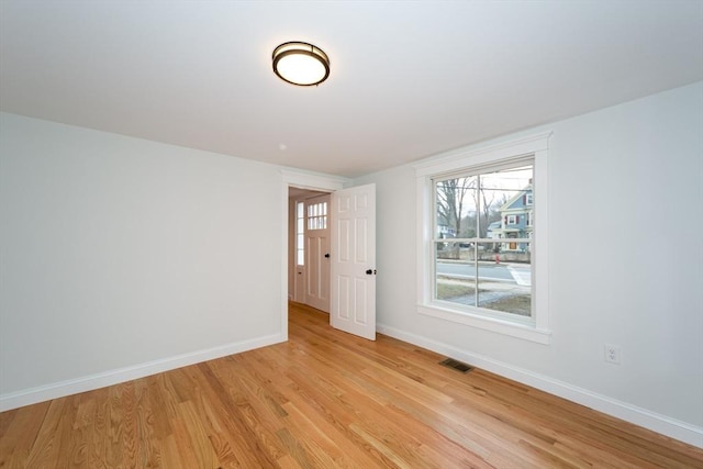 unfurnished room featuring light wood-style flooring, visible vents, and baseboards