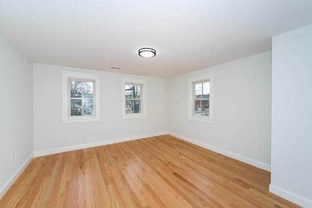 unfurnished room with light wood-style flooring, visible vents, and baseboards