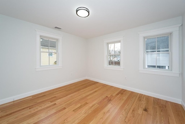 unfurnished room with light wood finished floors, visible vents, and baseboards