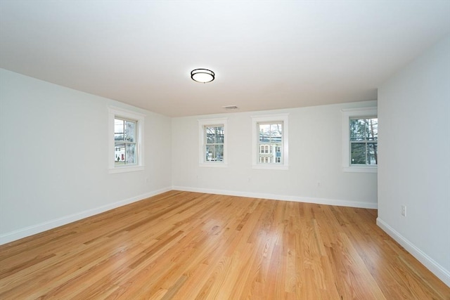 empty room featuring light wood finished floors, visible vents, and baseboards